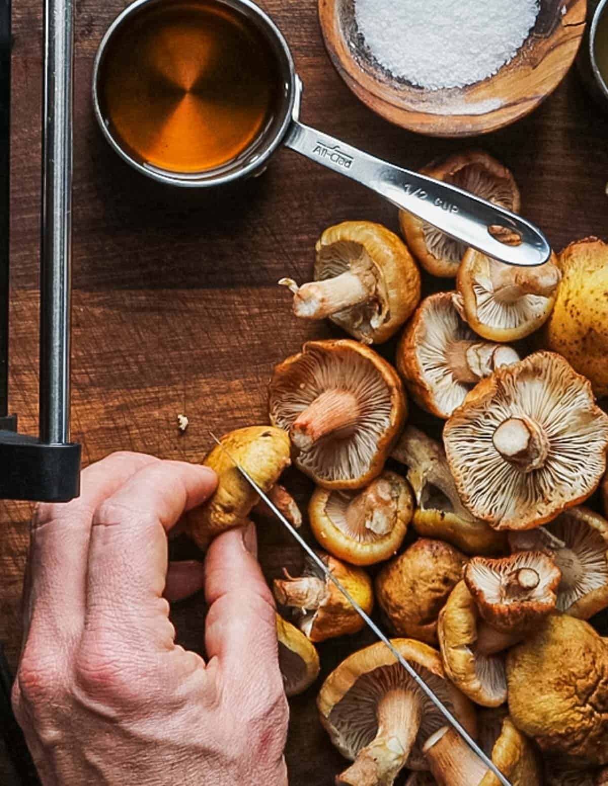 Cutting honey mushrooms in half with a knife. 