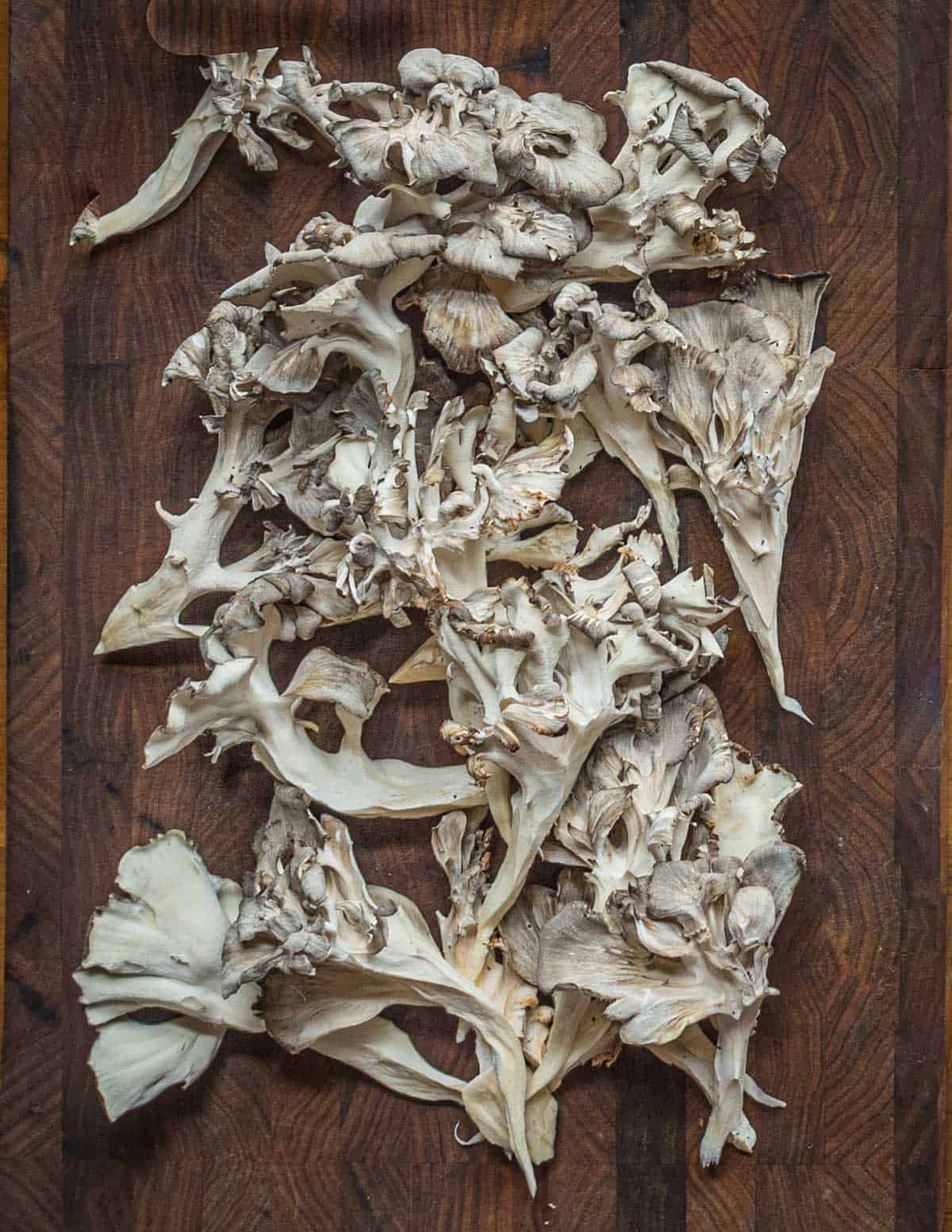Pieces of mushroom pulled apart on a cutting board.