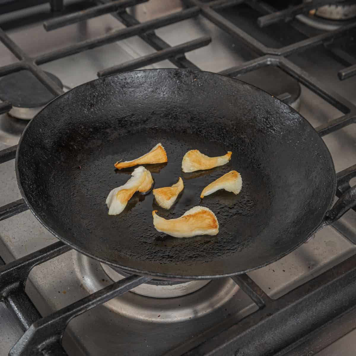 Cooking small pieces of lions mane mushroom in a carbon steel pan.