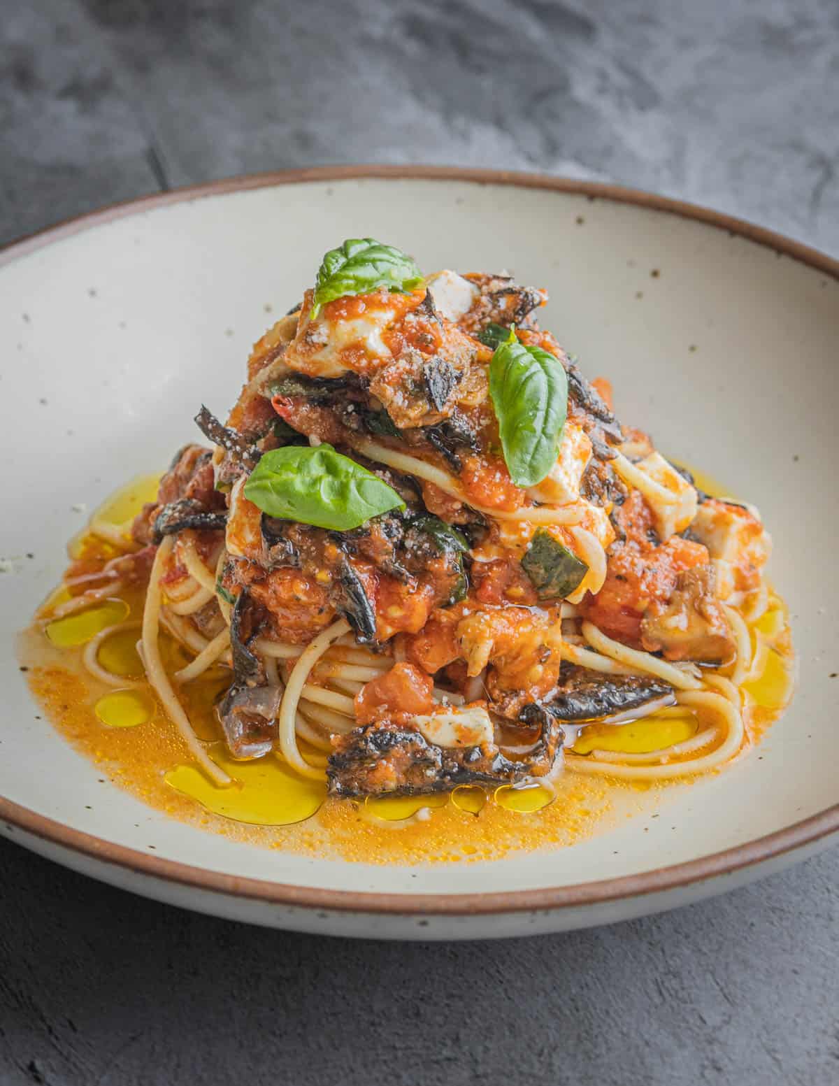 A bowl of pasta with black mushrooms and tomatoes.