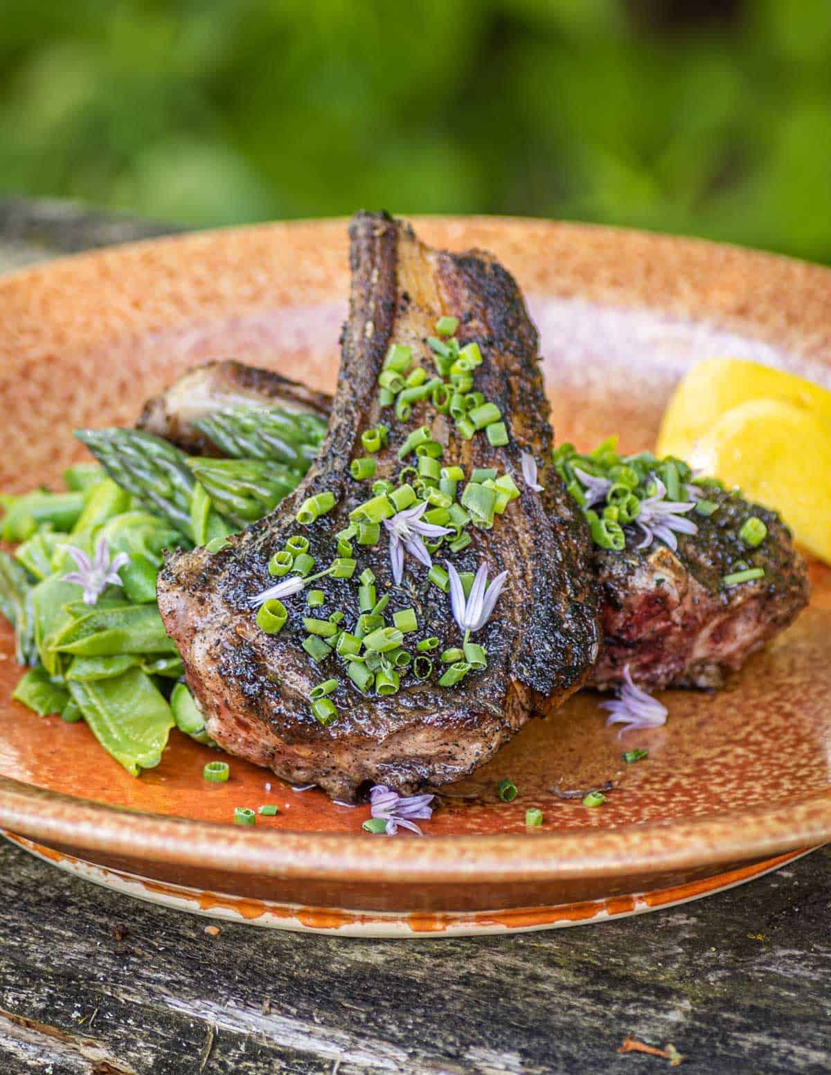 Mushroom crusted lamb chops on a plate with vegetables outside.