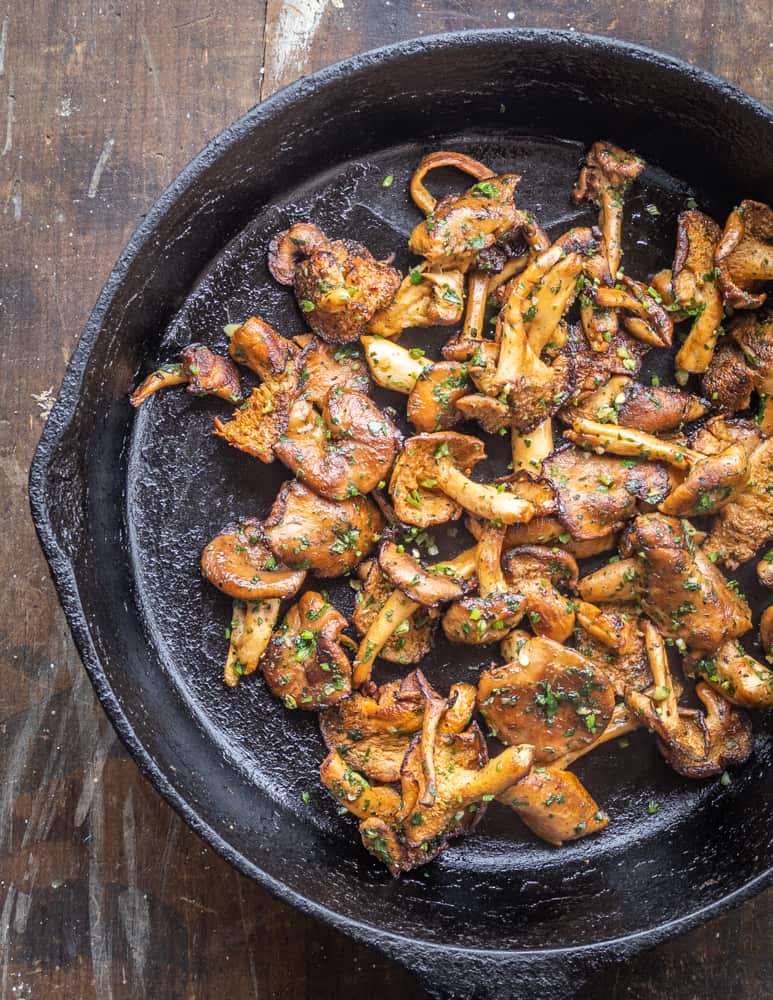 Wild hedgehog mushrooms with garlic and parsley in a pan