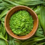 Ramp leaf pesto in a bowl surrounded by ramp leaves.