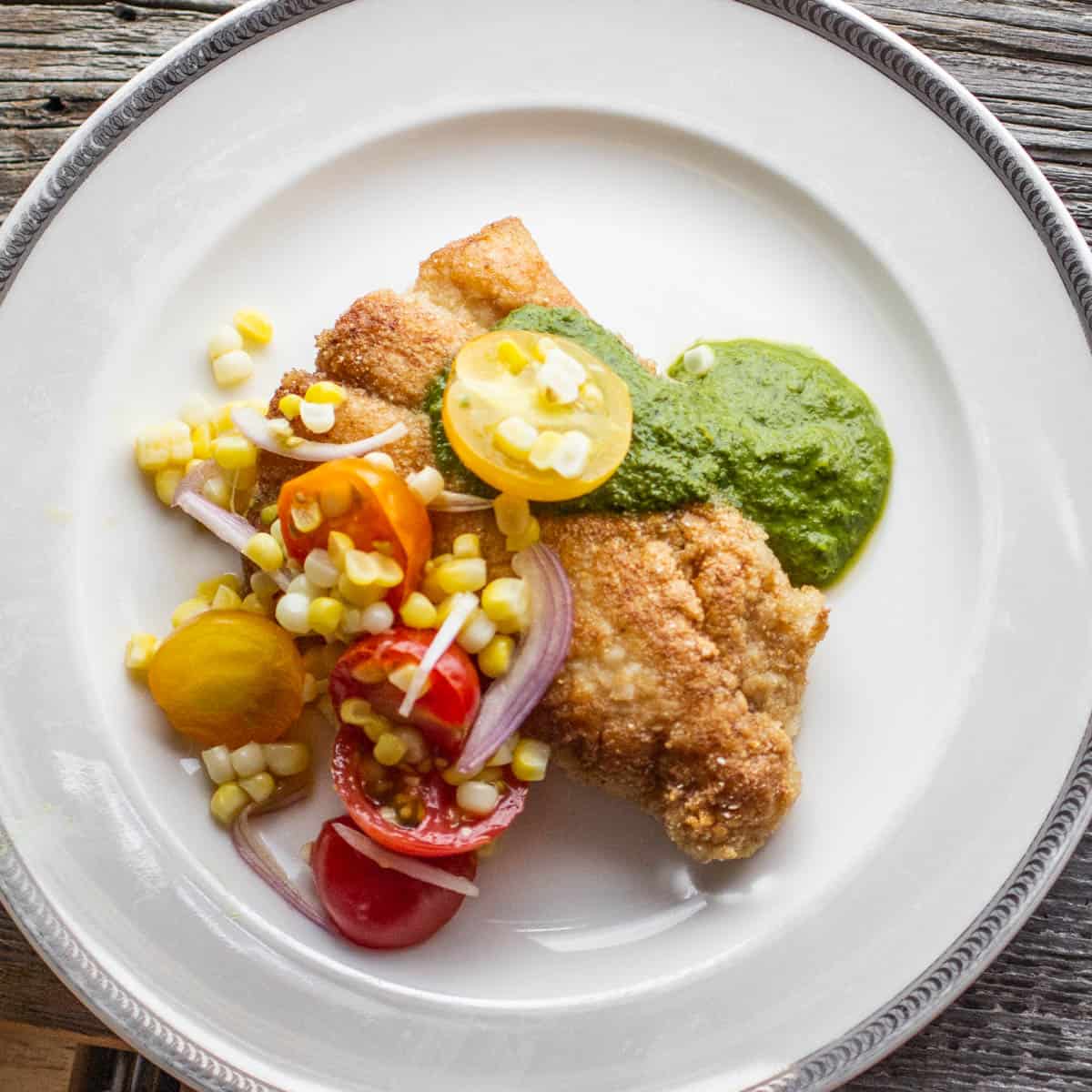 cornmeal fried catfish with green herb sauce on a plate