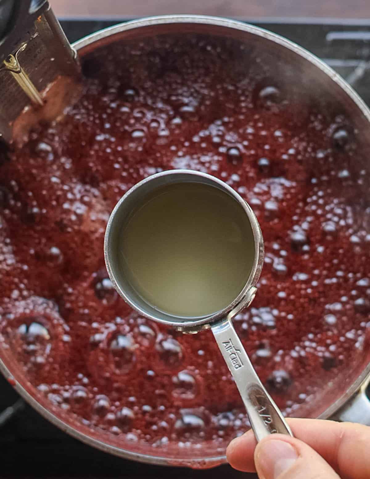Adding lemon juice to elderberry jelly after having successful set tests.