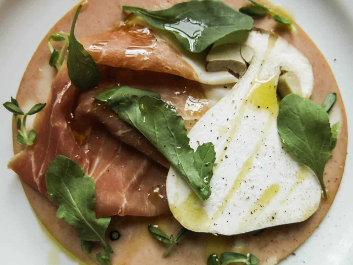 a plate of cured meats and sliced mushrooms 