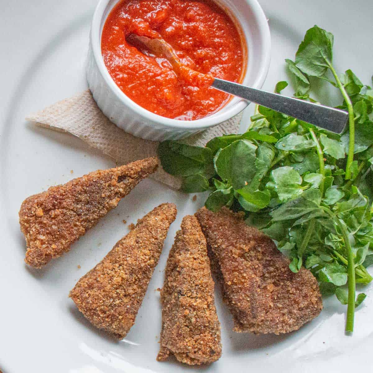 Baked breaded goat breast with tomato sauce 
