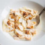 agnolotti pasta in a bowl with cream sauce and birch syrup and spoon