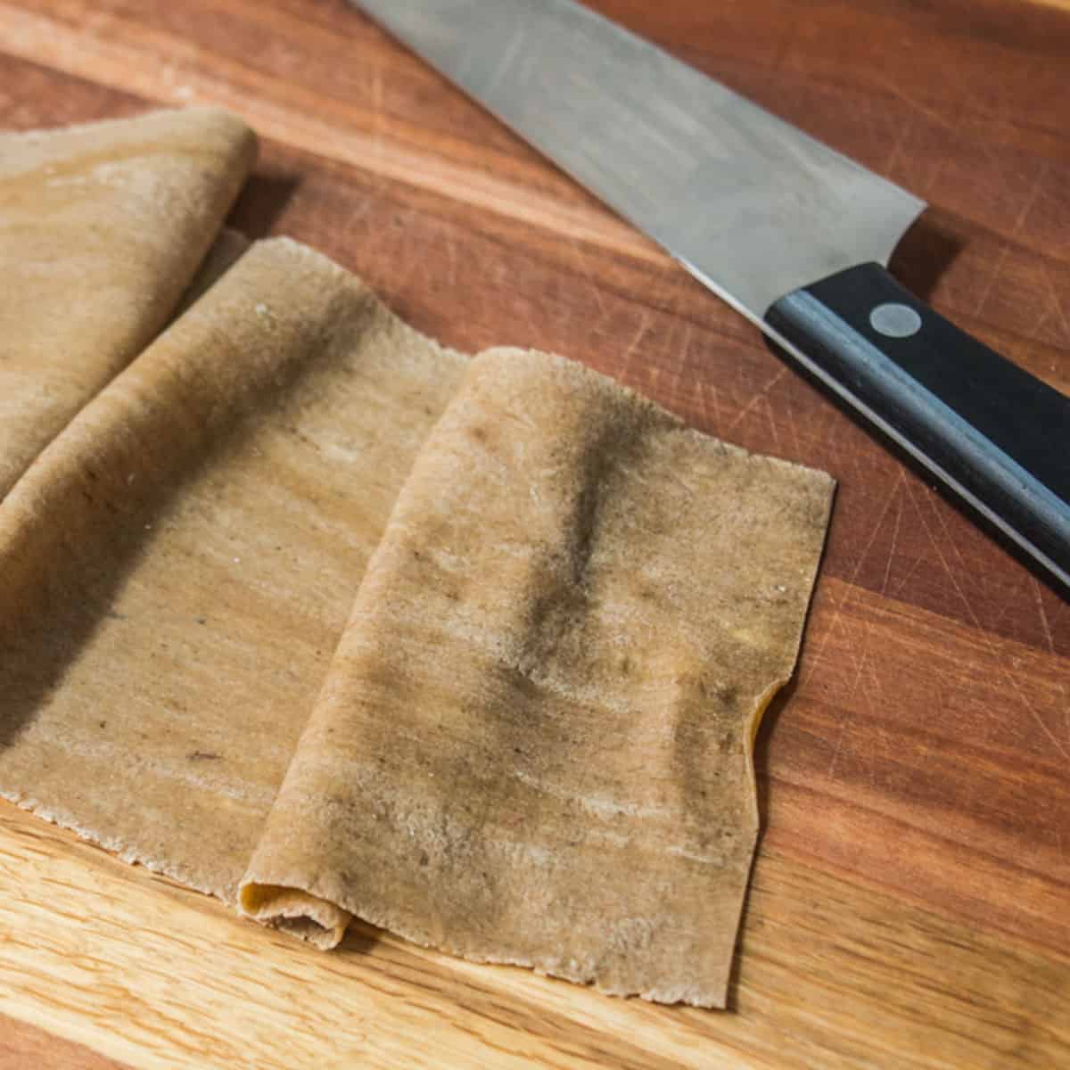 cutting a sheet of thin fresh pasta