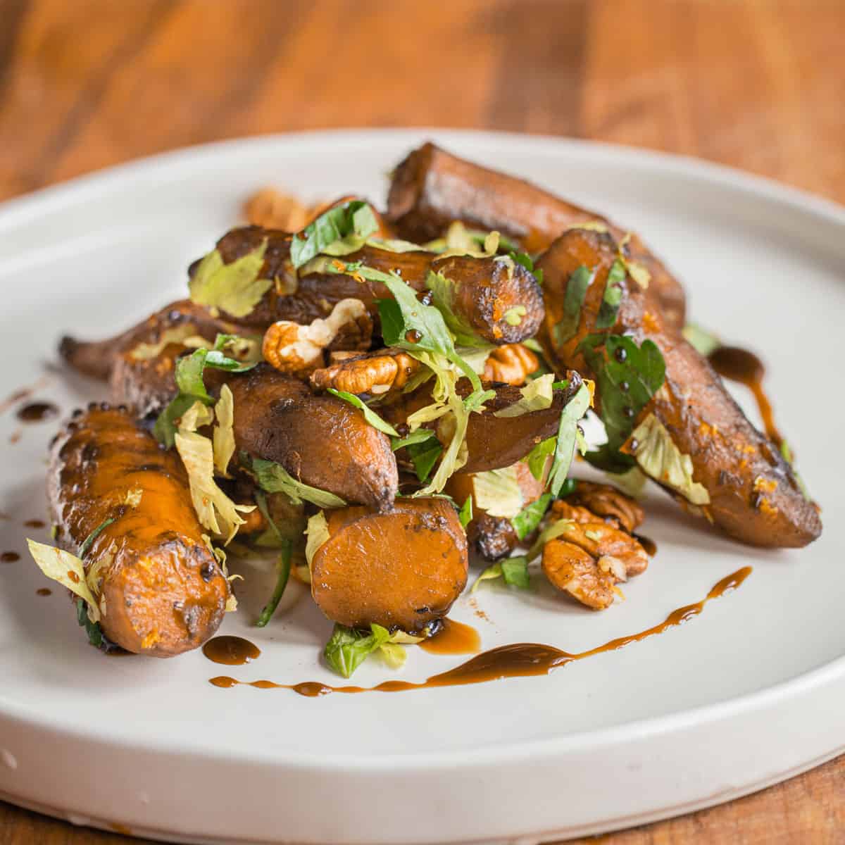 a pile of cooked sunchokes on a plate with herbs and syrup