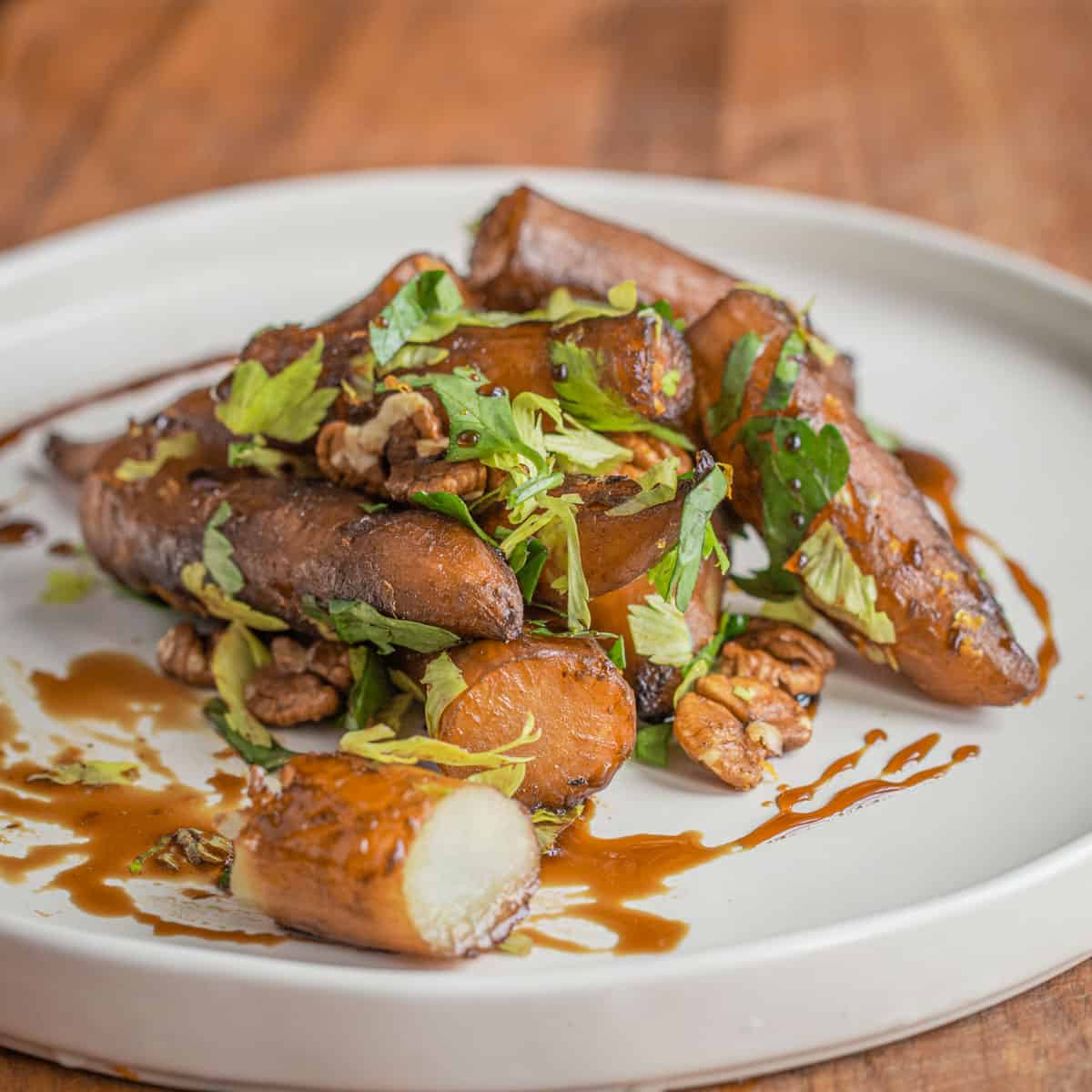 a pile of cooked sunchokes on a plate with herbs and syrup