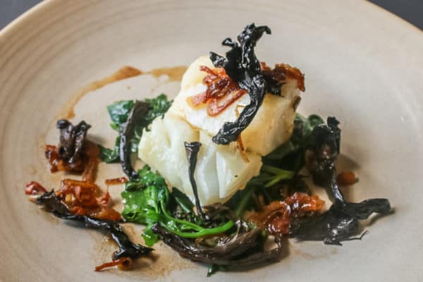 Skrei cod with wilted lambsquarters, caramelized shallots and black trumpet mushrooms
