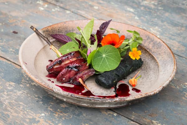 Smoked pigeon brochette with sunflower rolls, wild cherry sauce and foraged greens
