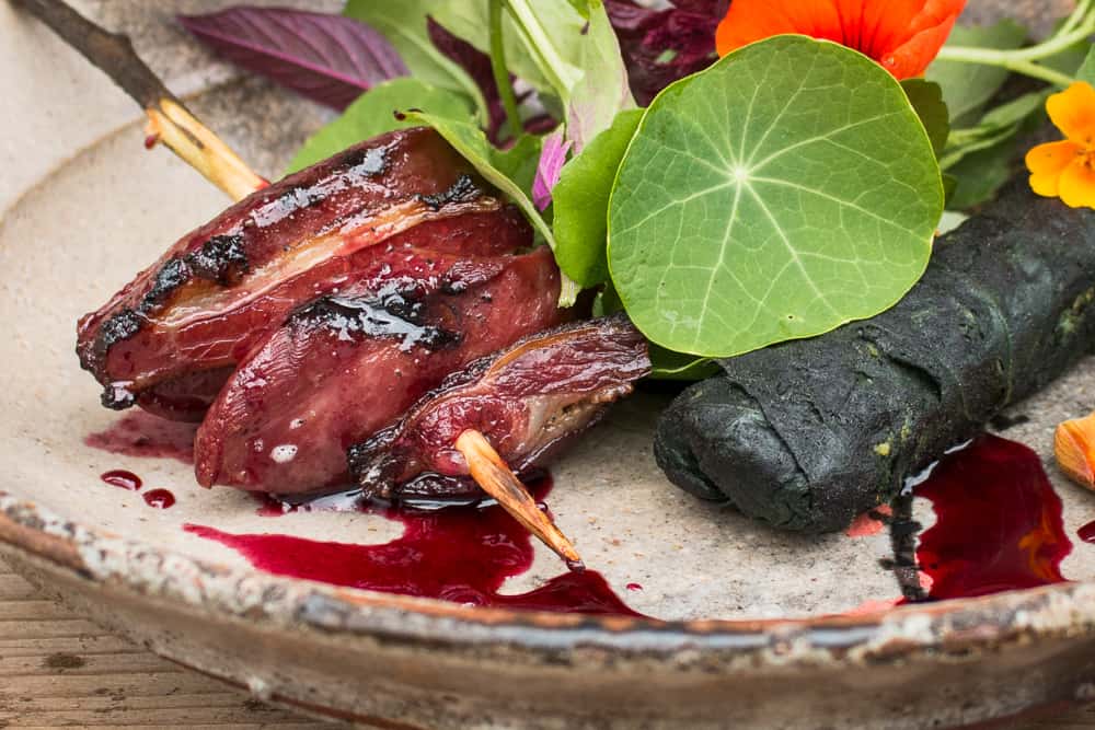 Smoked pigeon brochette with sunflower rolls, wild cherry sauce and foraged greens