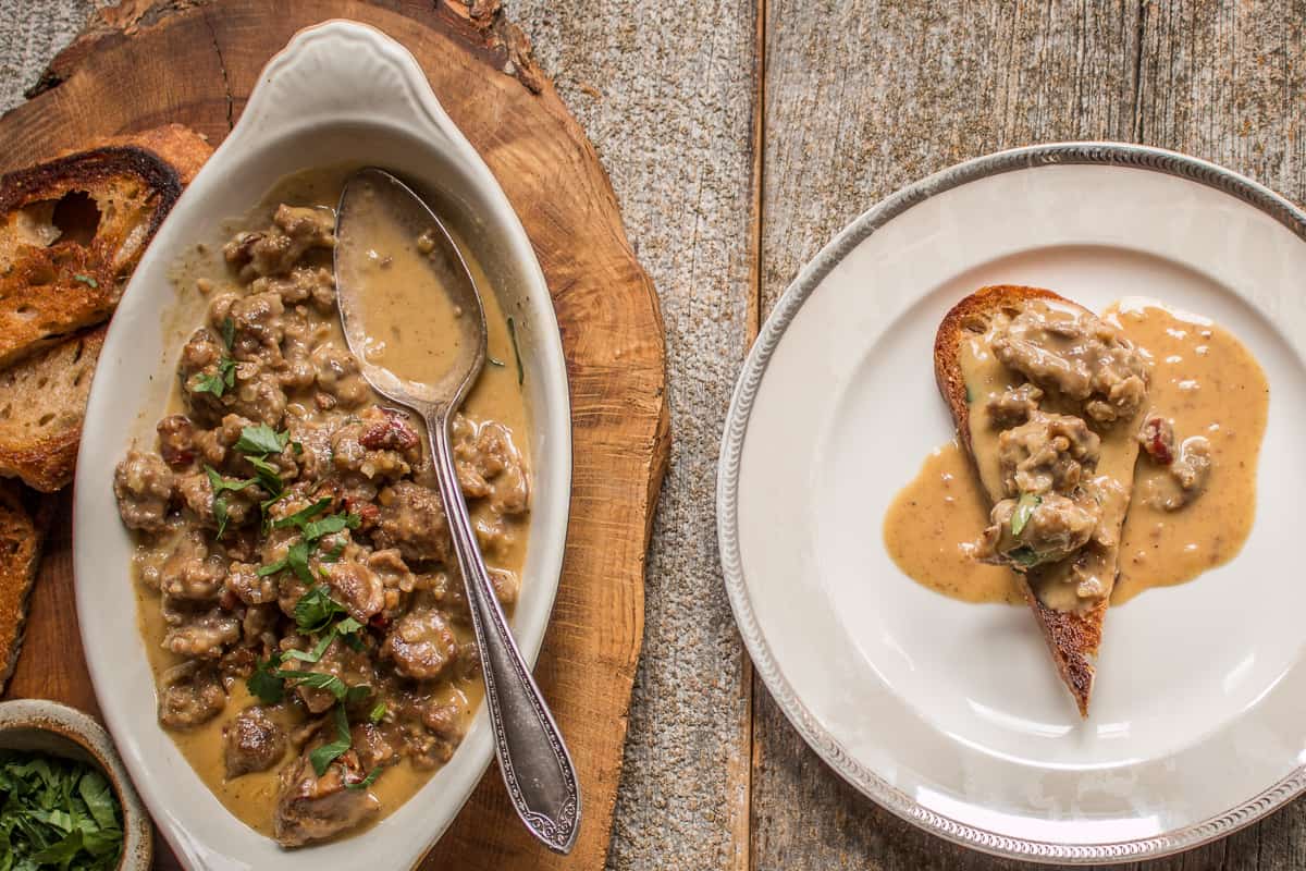 a dish of chicken livers being spooned over toast 