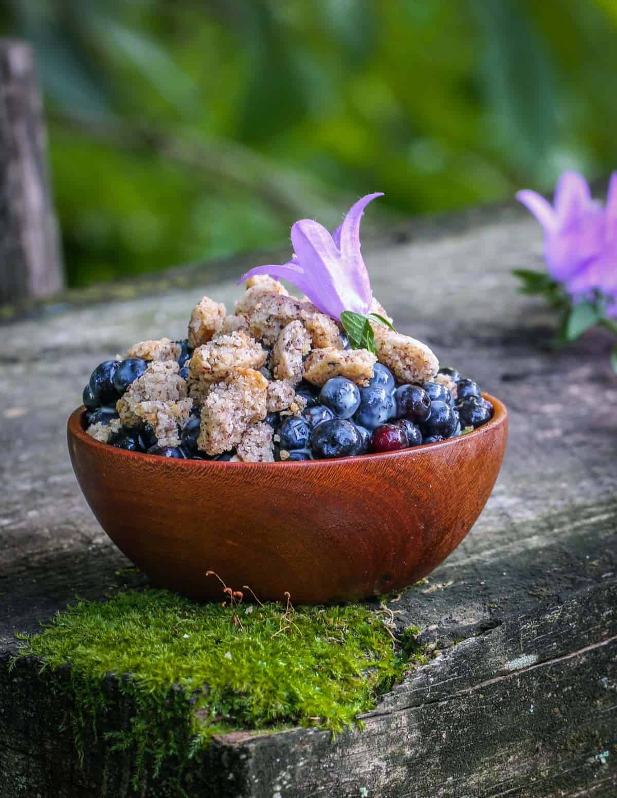 A bowl of fresh wild blueberries garnished with creeping bellflower flowers.