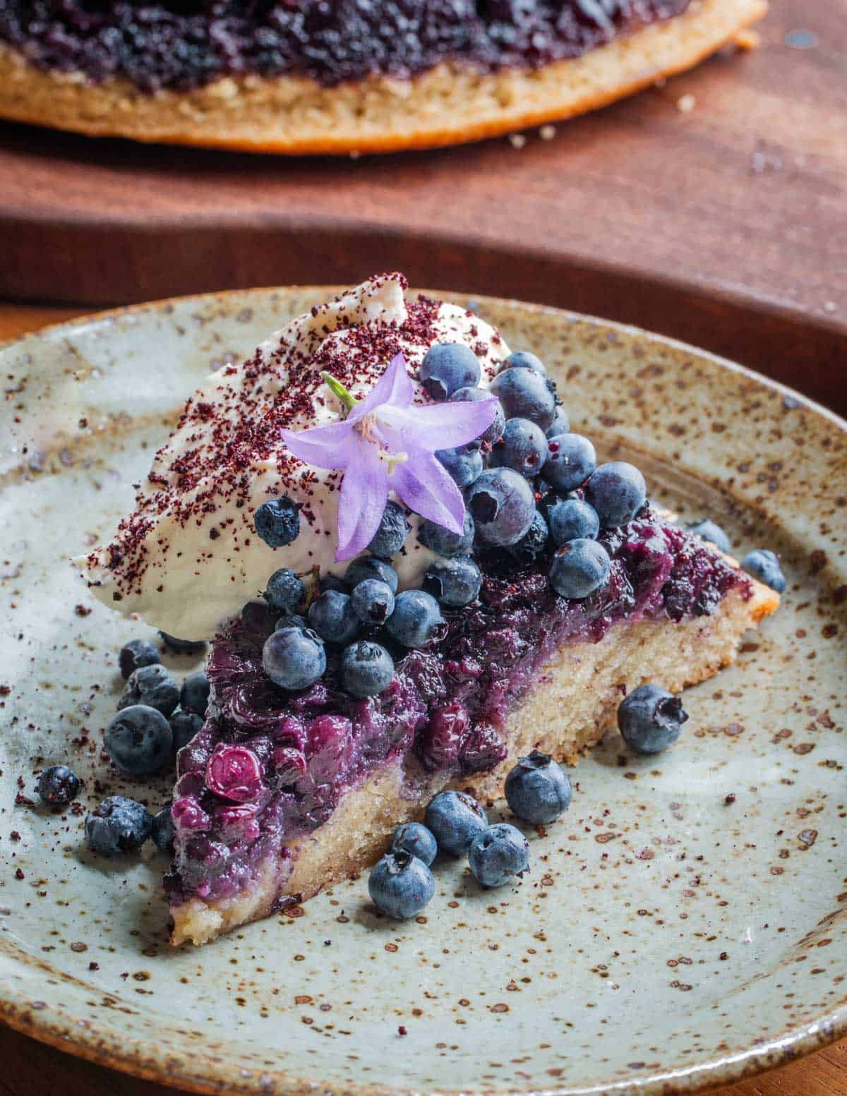 A close up image of blueberry upside down cake garnished with creeping bellflower flowers.