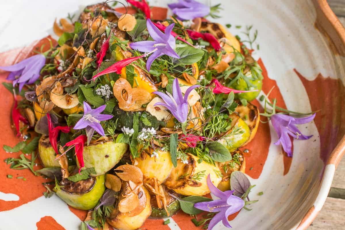 Summer squash salad with edible creeping bellflowers and garden herbs 