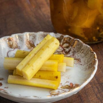 Yamagobo or pickled burdock root recipe cut up on a plate next to a jar of pickles.