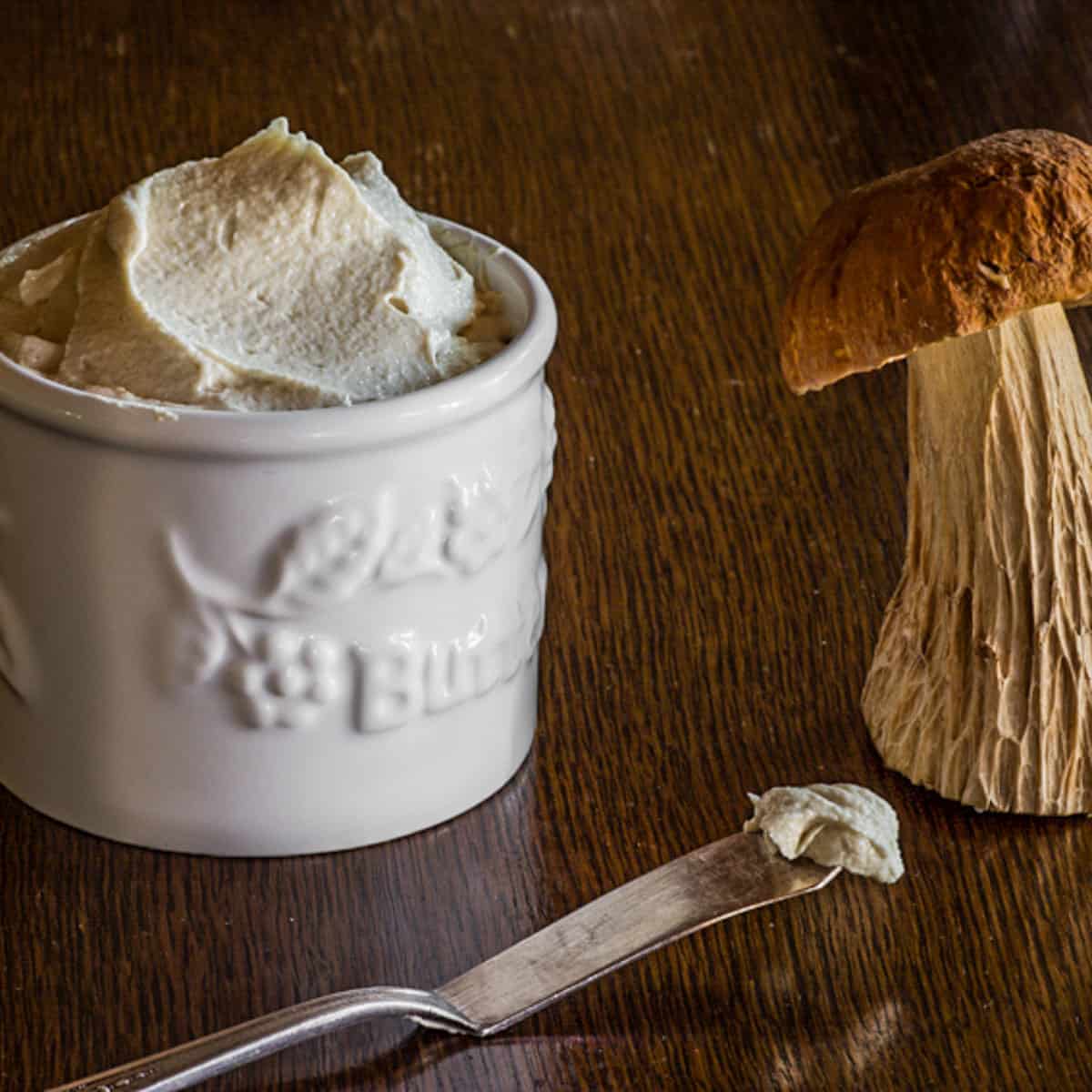mushroom butter in a crock next to a porcini mushroom