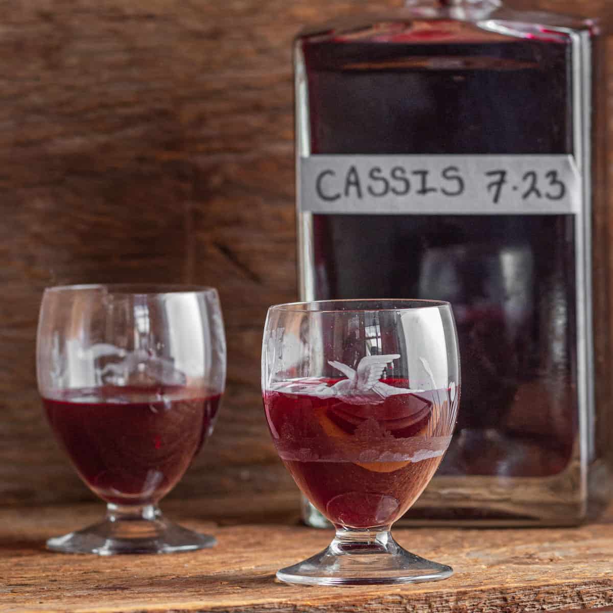 a glass of cassis next to a bowl of fruit 