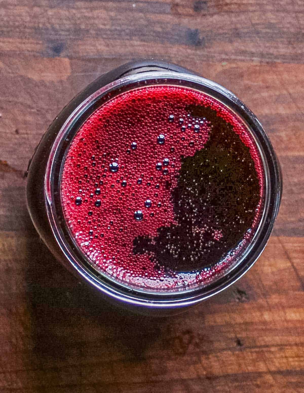 A top down image of red currant brandy in a mason jar. 