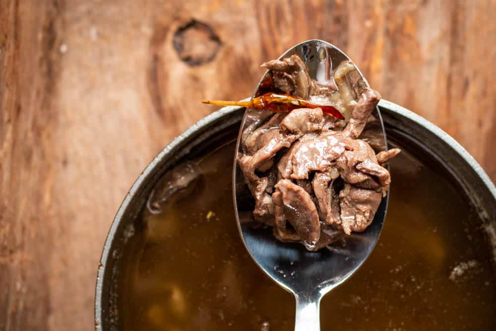 sliced venison heart confit on a spoon