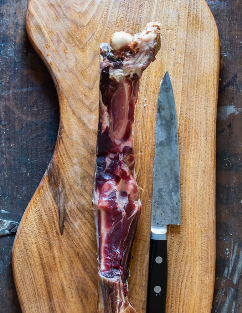smoked prosciutto bones on a cutting board with carbon steel knife 