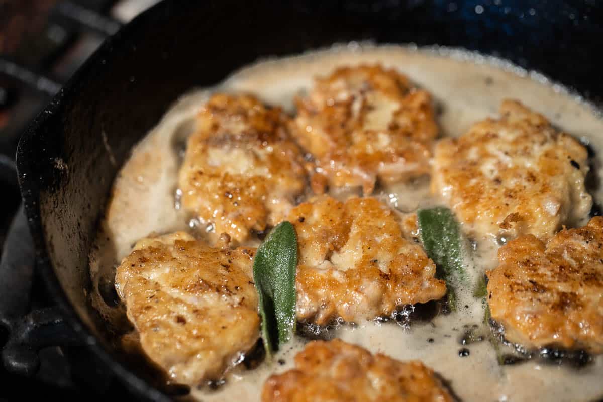 cooking brain fritters in a cast iron pan with sage leaves 