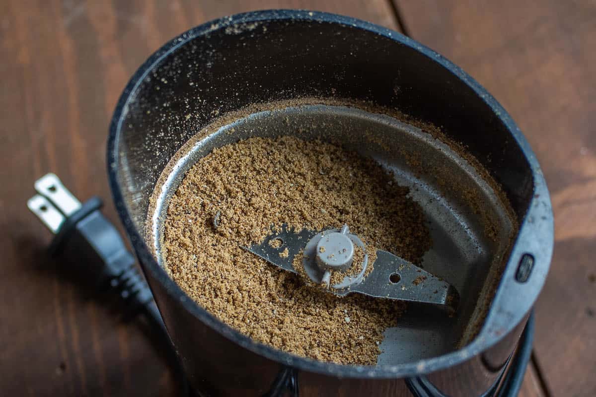 Grinding dried hackberries in a spice grinder