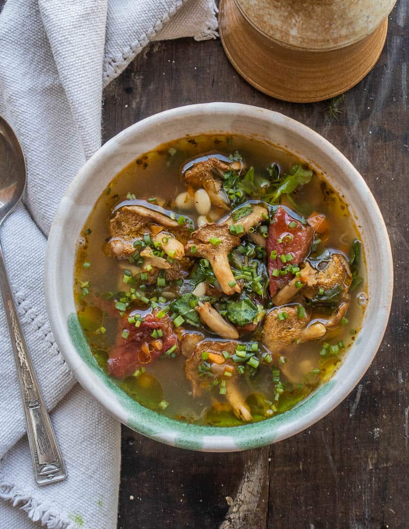 Hedgehog mushroom soup with foraged greens, beans and tomatoes