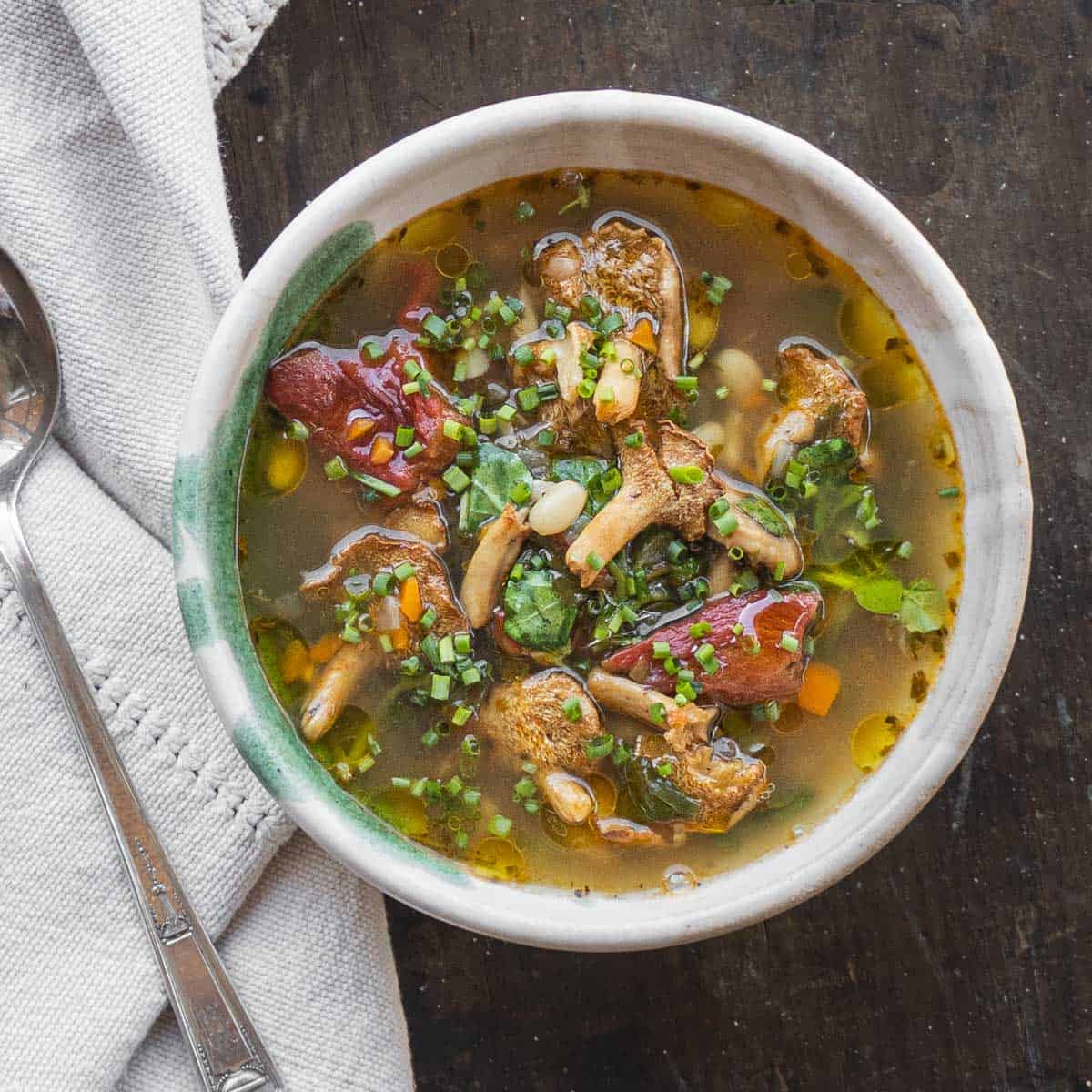 Hedgehog mushroom soup with foraged greens, beans and tomatoes