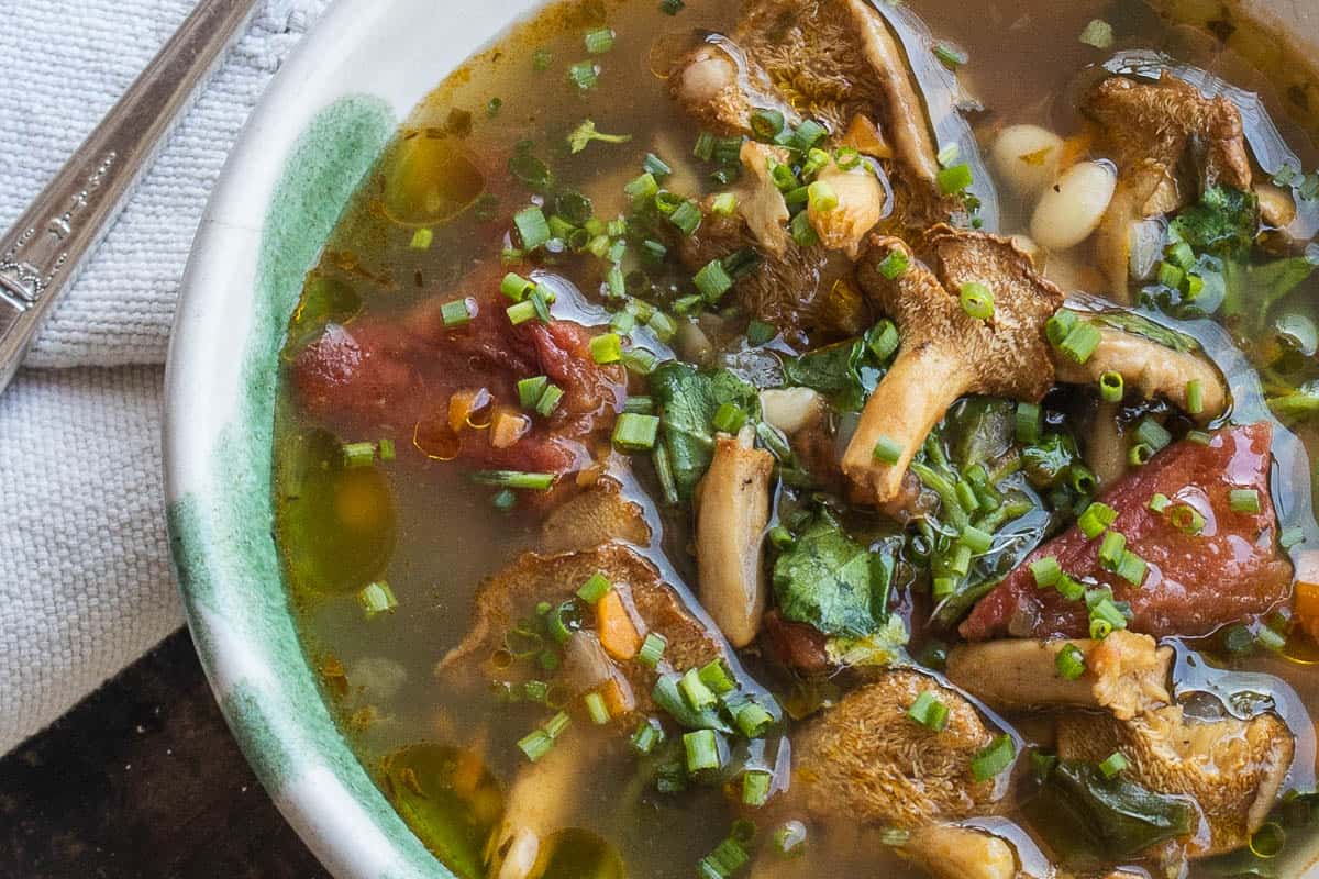 Hedgehog mushroom soup with foraged greens, beans and tomatoes