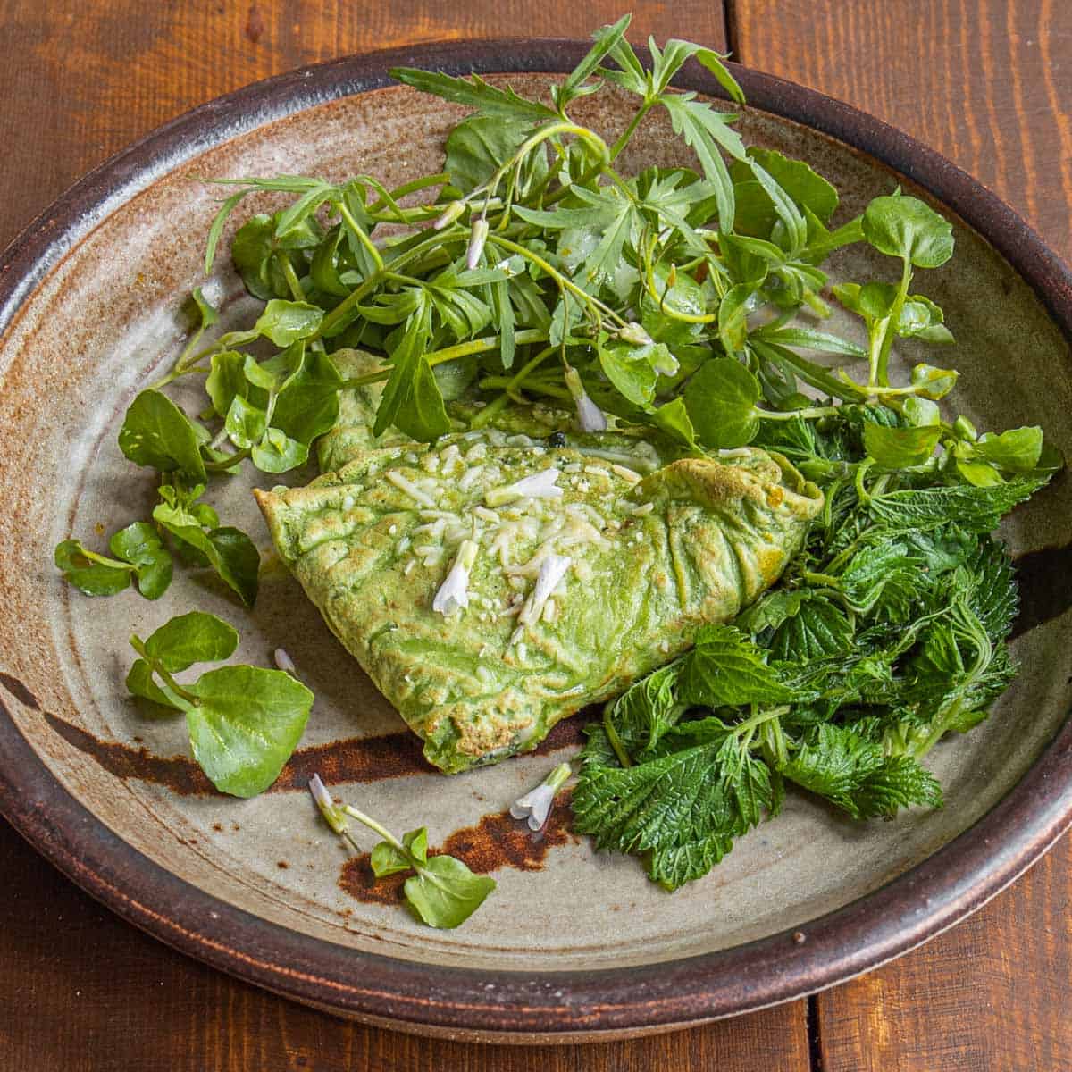 Green nettle crepes with nettle and goat cheese filling served with steamed nettles, toothwort and spring beauty
