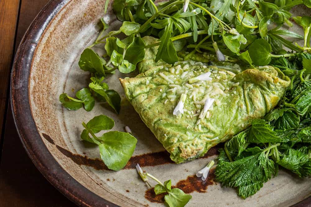 Green nettle crepes with nettle and goat cheese filling served with steamed nettles, toothwort and spring beauty