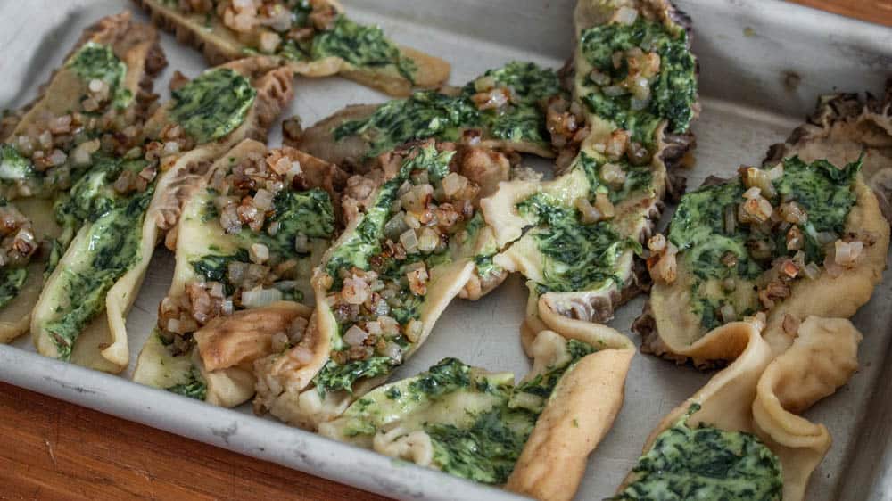 Spreading morels with garlic herb butter before baking