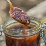 young pine cones in syrup in a jar drizzling off a spoon.