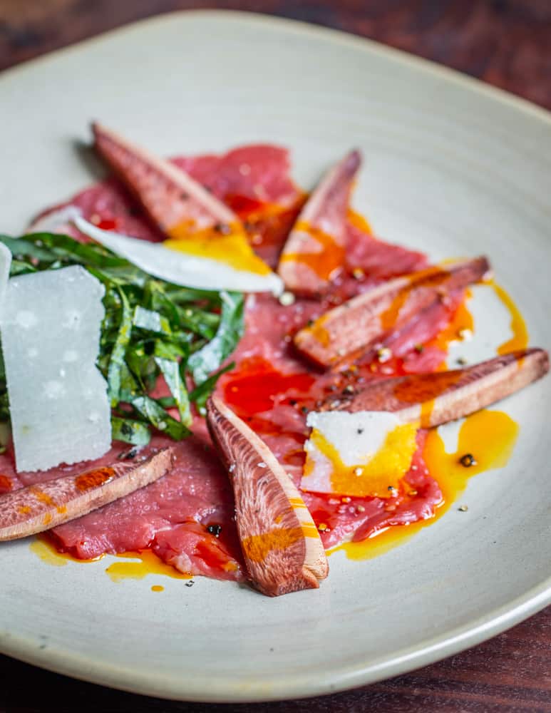 Beef carpaccio with beefsteak mushrooms, acorn oil, parmesan and shaved sochan