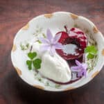 Apples poached in wild grape juice with maple sugar creme fraiche bell flower and wood sorrel