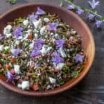 Cooked purslane salad with tomatoes, feta cheese, olive oil, and creeping bellflower flowers