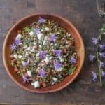 Cooked purslane salad with tomatoes, feta cheese, olive oil, and creeping bellflower flowers