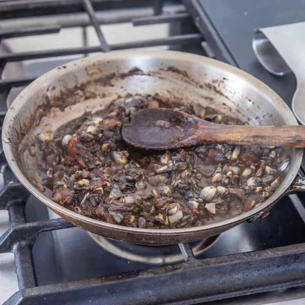 cooking huitlacoche in a pan with tomatoes and garlic
