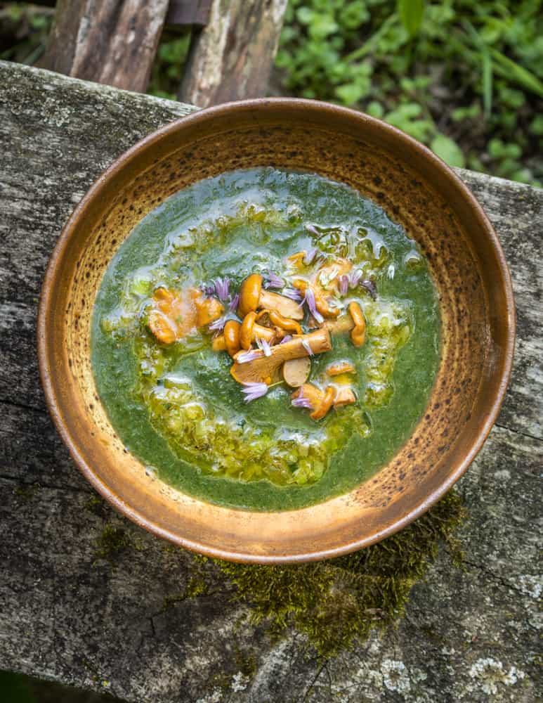 a bowl of green soup with mushrooms and melted butter. 