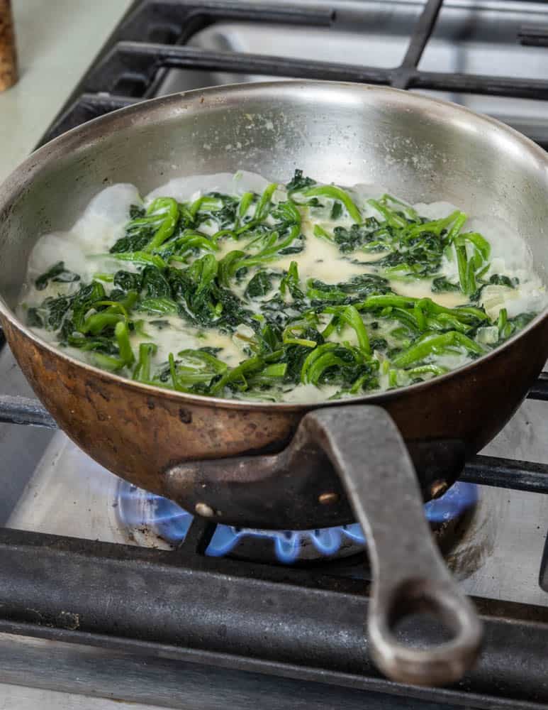 greens cooking in a pan with cream 