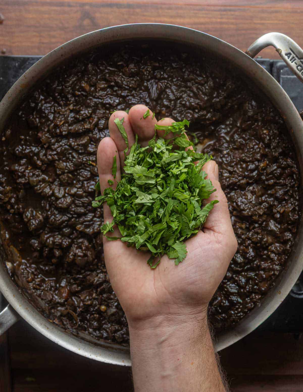 Adding fresh chopped cilantro to a pan of cooked corn mushrooms.