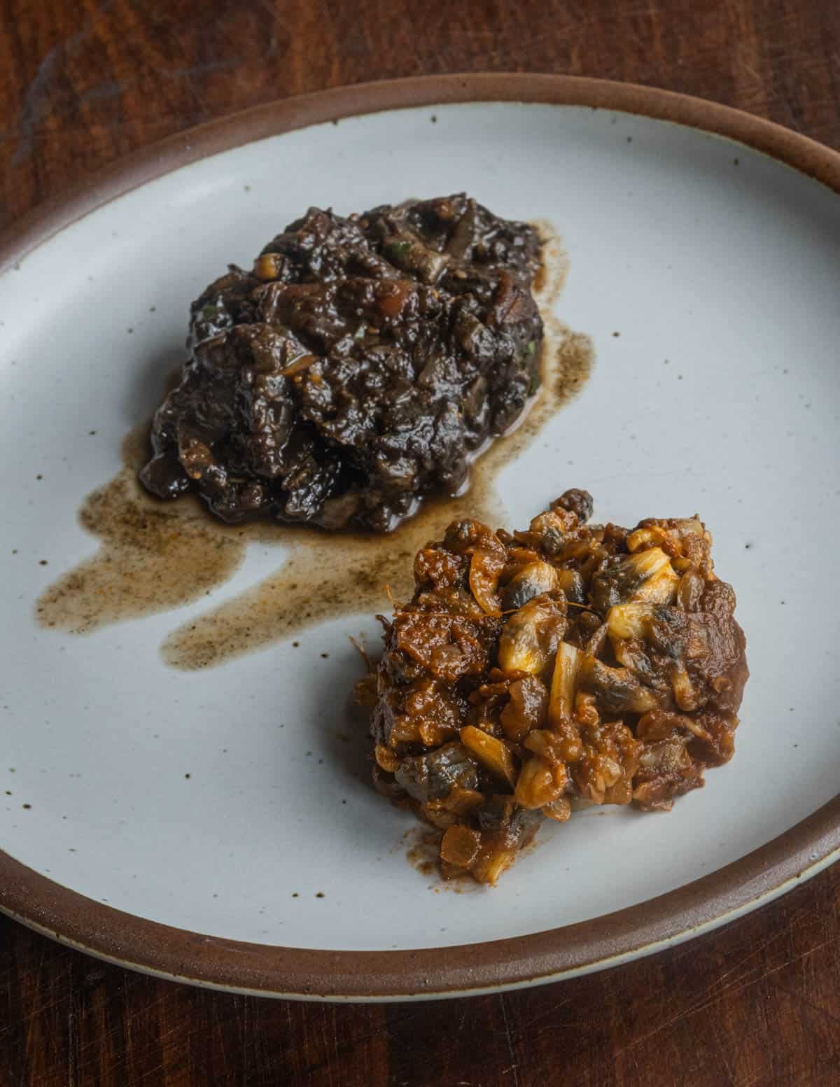 Frozen and fresh cooked huitlacoche next to each other on a plate showing the color differences between fresh and frozen mushrooms.
