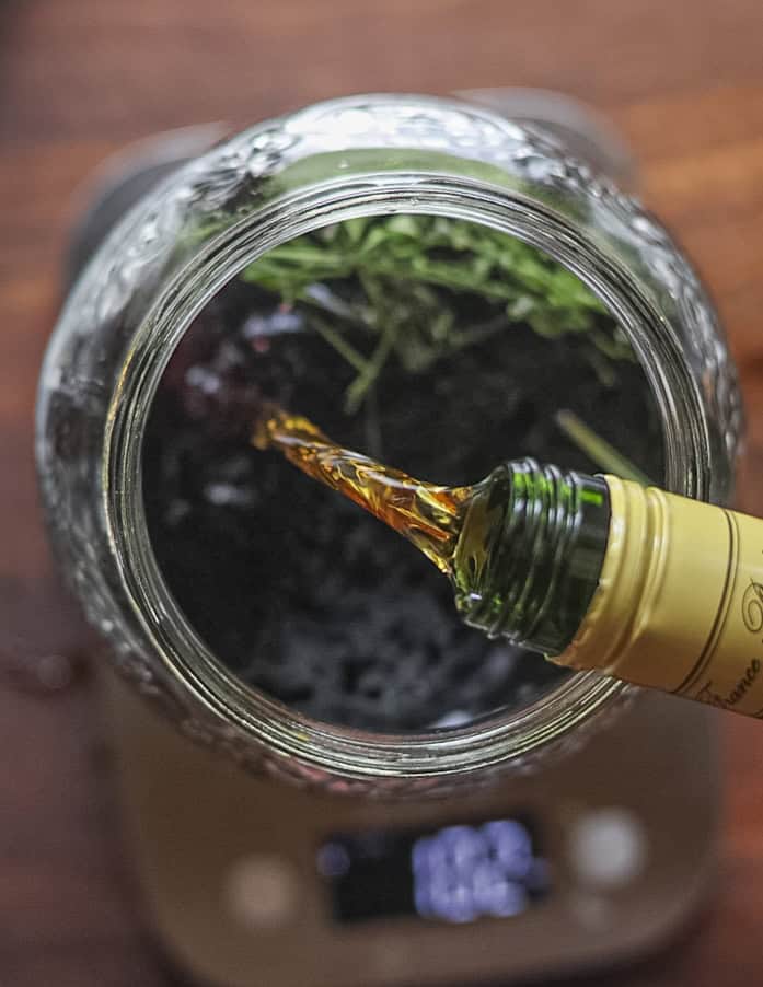 Adding brandy to a jar of green walnut wine. 