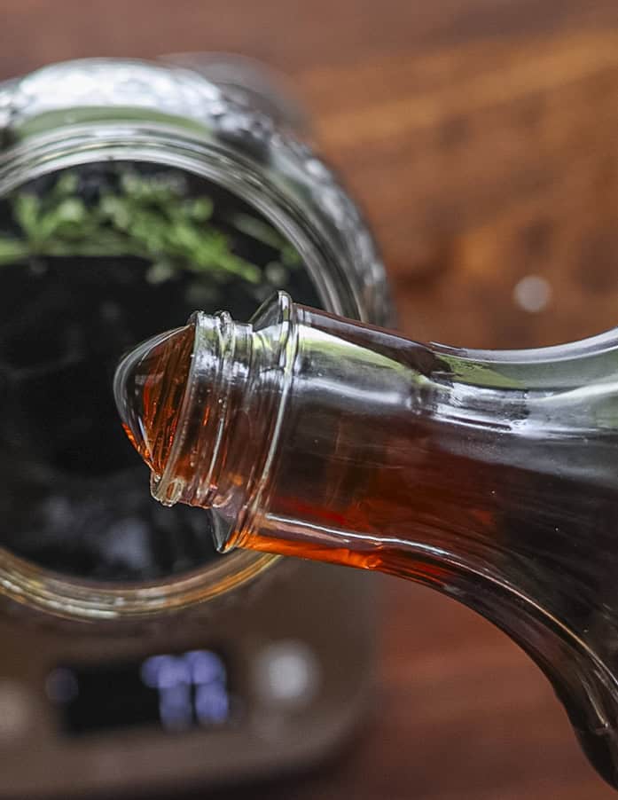 Adding maple syrup to a jar of walnut wine. 