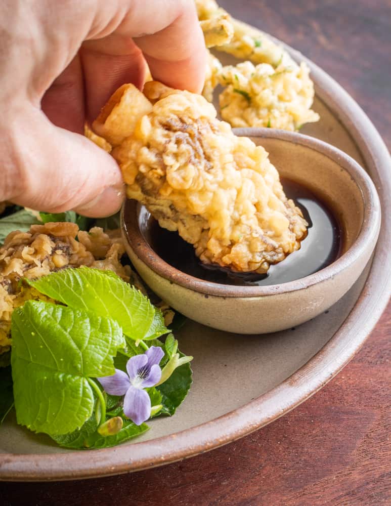 Dipping morel mushroom tempura in a sauce made from ramp garum 