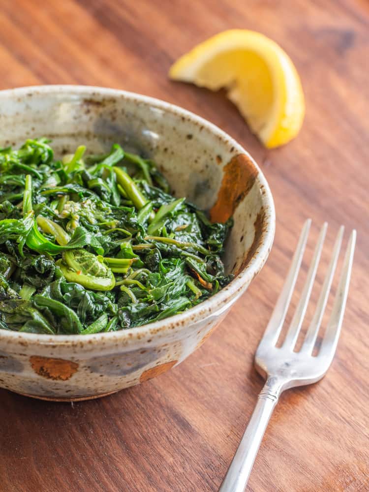 Foraged greens cooked with lemon and olive oil in a stoneware bowl